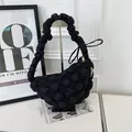 Detail view of a black quilted bubble hobo bag with a ruffled handle on a display stand - Black