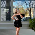 Detalle de modelo con vestido ajustado negro de un hombro y dobladillo con volantes - S / Vestidos / Negro