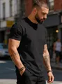 Detailed view of plain black cotton crew neck t-shirt on male model in street setting - Black