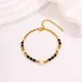 Bracelet élégant en acier titane doré avec perles noires facettées et une perle blanche - Bracelet en Perles Noires