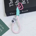 Primo piano dettagliato di un portachiavi in corda intrecciata con moschettone rosa. - Stile Contrasto Rosa E Blu Teal (Huayang 6)