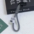 Dettaglio di un cordino per cellulare in corda intrecciata con rete e etichetta - Stile Contrasto Grigio E Bianco (Huayang 9)