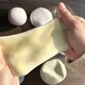 Primer plano de manos estirando un juguete mochi squishy amarillo para estrés - Amarillo