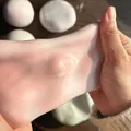 Gros plan de mains étirant un jouet mochi squishy rose souple montrant son élasticité. - Orange