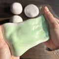 Gros plan de mains étirant un jouet mochi mou vert clair pour soulager le stress - Balle Mochi Squishy / 1 Pièce / Vert