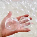 Hand holding two 4cm clear hollow TPR squishy balls for DIY stress relief toys. - 5.5cm (With Lid) / Clear