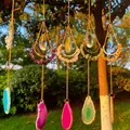 Detail view of colorful hanging crystal suncatchers with crescent moons and agate slices - Purple
