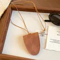 Nahaufnahme brauner Brillenhalter-Anhänger aus Wildleder mit Kordel auf Tablett - Einfacher Wildleder-Stil / Halskette-Kaffee
