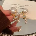 Nahaufnahme eleganter französischer Perlenohrringe mit Kristallen auf Spiegel - Quasten Perle Ohrstecker / Gold-Weiß