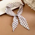 Detalle de una bufanda de seda estrecha con estampado floral francés y una perla decorada - Flor Blanca
