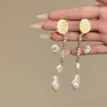 Gros plan de boucles d'oreilles pendantes en perles baroques vintage avec puces - Tige d'oreille en argent-Blanc / Or