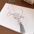 Detailed view of stainless steel tassel necklace with elegant white beads on vintage paper - Necklace-Silver-White