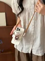 Detailed shot of a plush teddy bear pendant on a cream phone case with crossbody strap - Accessory-Coffee