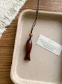 Détail macro d'un pendentif en bois fait main posé sur un plateau rustique texturé. - Poisson Ovale / Marron