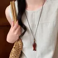 Dettaglio di una collana con ciondolo a pesce in legno su top in lino. - Ciondolo a Pesce Ovale / Marrone