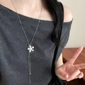 Vue détaillée d'un collier pendentif fleur argenté porté avec un haut gris élégant - Argent