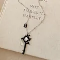 Close-up of a black swallow key pendant necklace with rhinestone on a vintage book - Swallow Key Style / Silver Black Swallow