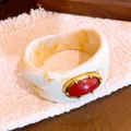 Detalle de cerca de un brazalete de resina jaspeada con un cabujón rojo vintage - Bangle / Marfil