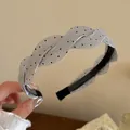 Primer plano detallado de una diadema de satén trenzada plateada con lunares negros chic - Estilo Lunares Gris / Gris