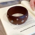 Dunkelbrauner Holzarmreif im Ethno-Stil mit silberfarbenen Nieten für einen Vintage-Look. - Braun