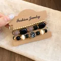 Close-up of a three-layered acrylic beaded bracelet set displayed on a kraft card holder - 4# Triple-Layered Style / Set of 4 / Black-Gray