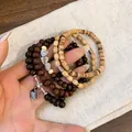 Macro detail of Bohemian multilayered beaded bracelets with wood beads and charms - Butterfly Charm (1#) / Brown-Coffee
