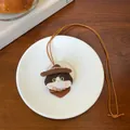 Gedetailleerde close-up van een schattige geborduurde kattenpop ketting op schotel - Ketting-Koffie