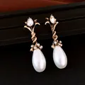 Close-up van elegante bloemen oorbellen met witte druppelparels en kristallen - Oorbellen-Antiekgoud-Wit