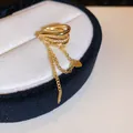 Detailed view of a gold ear cuff with zircon inlay and dangling tassel chains - Triple Heart Style (11#) / Single Piece / Gold