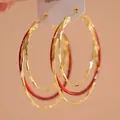 Close-up van elegante goud- en roodkleurige meerlagige oorringen op een displaykaart - Goud-Rood