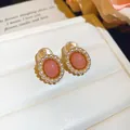 Detailed view of elegant oval pink resin earrings with pearl border on white cushion - Clip-On Earrings / Pink