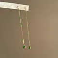Nahaufnahme eleganter langer Quastenohrringe mit grünen Zirkonia-Perlen und Goldketten - Lange Quasten Ohrstecker (HE35674) / Gold-Grün