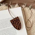 Macro view of stylish leopard print leather clochette necklace on a book background - Brown Leopard Print Bow Necklace
