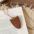 Detail of a minimalist brown leather necklace eyeglass holder on a white book background. - Matte Coffee (Eyeglass Holder Necklace) / Necklace-Coffee