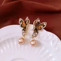 Elegante 14k vergulde vlinder oorbellen met parelhanger en zirkonia accenten - Oorknopjes (7#) / Goudbruin