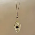 Détail d'un pendentif géométrique doré évidé avec perle œil de tigre. - Or - Forme de Losange