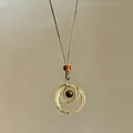 Gros plan d'un pendentif rétro en œil de tigre avec cercles dorés et cordon brun - Or-Rond