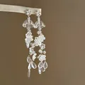 Vue détaillée d'élégantes boucles d'oreilles pompons muguet avec accents floraux. - Style Muguet Fleur Pompon / Blanc (Tige en Argent)