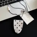 Close-up detail of leather polka dot pendant necklace featuring metallic bow tie element. - Silver