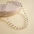 Detailed view of clear glass bead necklace with colorful accents on beige background - 10mm / White with Multicolored Stones