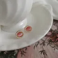 Macro detail of retro oval earrings with pink cat-eye stone and small pearl border - Silver Post Style / Pink