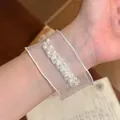 Nahaufnahme eines eleganten Armbands aus weißem Schneegarn mit feinen Perlendetails. - Weiß