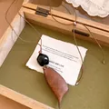 Detailweergave van de vintage houten hanger ketting met een bruin lederen koordje - Houten Peul Stijl (Koffie-Peul)