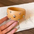 Detalle de brazalete marrón claro con remaches plateados redondos y en forma de rombo - Caqui