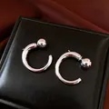 Nahaufnahme der minimalistischen silbernen C-förmigen Creolen mit polierter Kugelverzierung - Silber (Silberstift) / Silber
