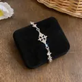 Close-up van zilverkleurige armband met fonkelende ruitvormige kristallen hangers op fluweel. - Zilver-Wit