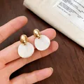 Gedetailleerde close-up van elegante goud en witte gemarmerde hars druppeloorbellen - Geometrische Ronde Druppelstijl (2#) / Goud+Wit