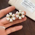 Close-up van elegante witte emaille bloemknopjes met goudkleurig hart op de vingers. - Holle Bloem Stijl (1#) / Goud+Wit