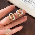 Detailopname van elegante goud-witte in elkaar grijpende bloemenoorknopjes - Vergrendelde Dubbele Ringstijl (3#) / Goud+Wit