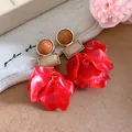 Detailed view of statement red acrylic flower petal earrings with geometric gold-tone studs - Red